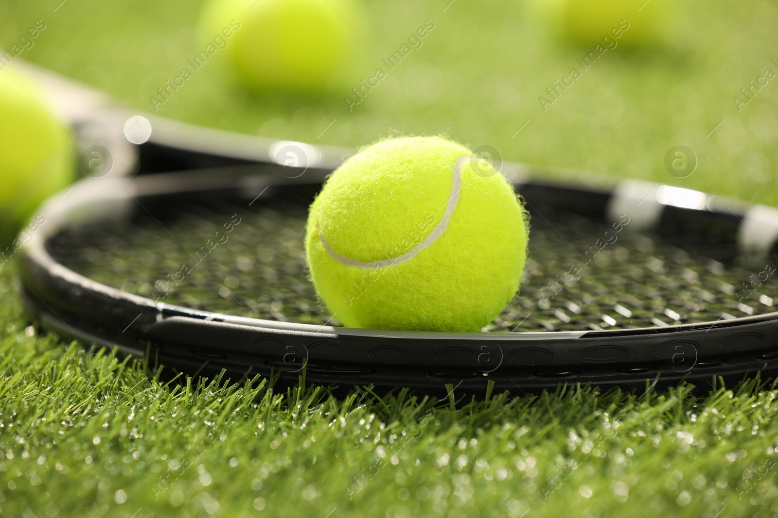 Photo of Tennis racket and ball on green artificial grass, closeup