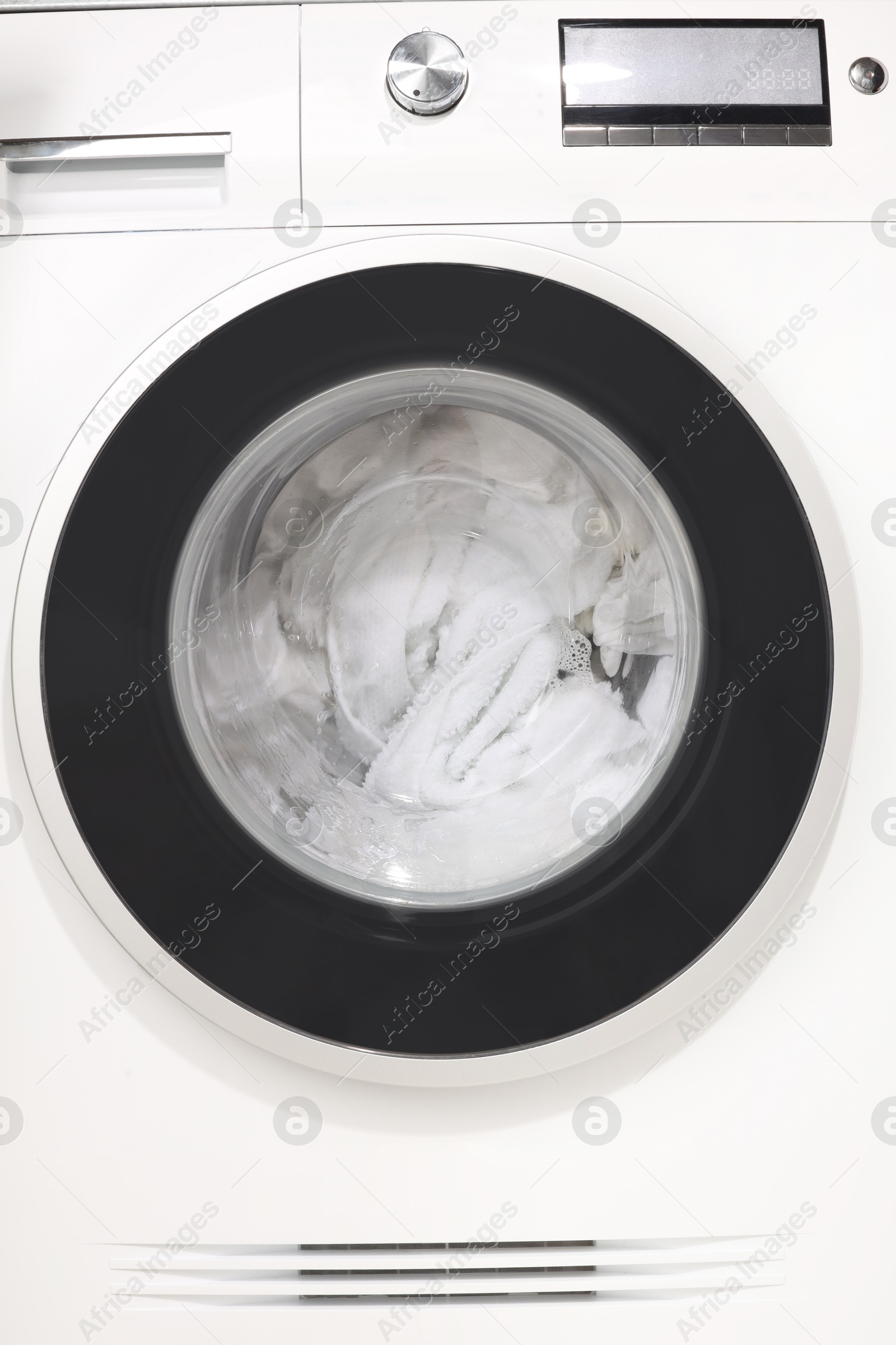 Photo of Washing machine with clothes as background, closeup