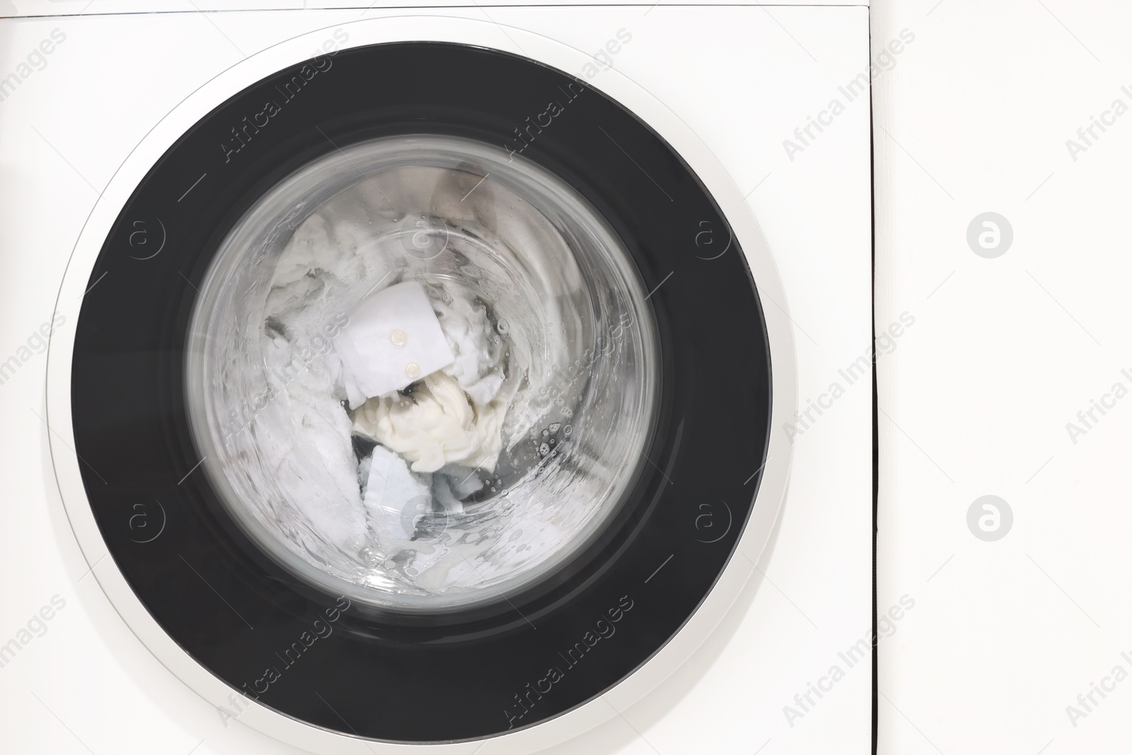 Photo of Washing machine with clothes as background, closeup