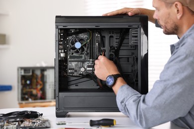 Man installing fan into computer at white table