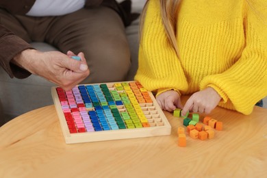 Grandpa and his granddaughter playing with math game Times table tray at home, closeup