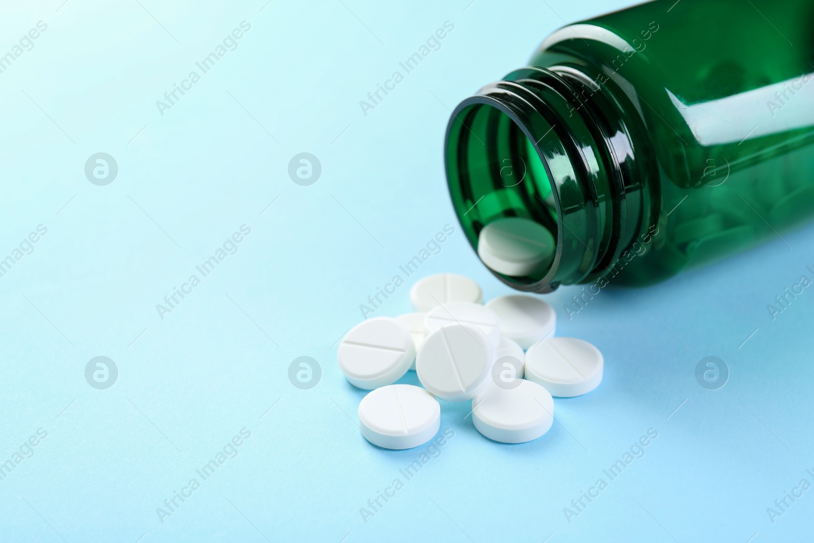 Photo of Medical bottle with antibiotic pills on light blue background, closeup. Space for text