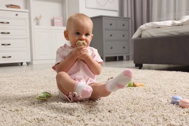 Photo of Cute little baby with rattles on floor indoors