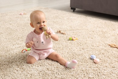 Photo of Cute little baby with rattles on floor indoors, space for text