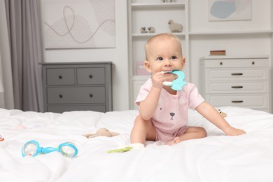 Photo of Cute little baby with rattles on bed indoors