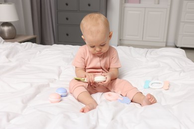 Photo of Cute little baby with rattles on bed indoors