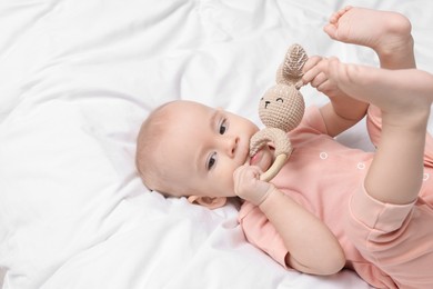 Photo of Cute little baby with rattle on bed indoors, space for text