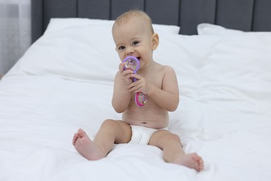 Photo of Cute little baby with rattle on bed indoors