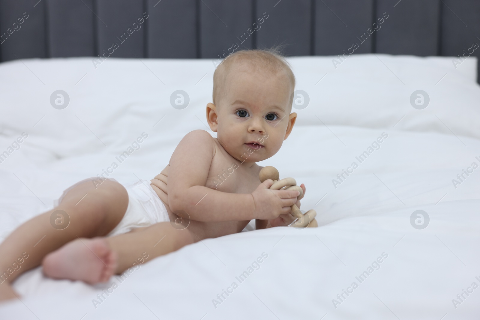 Photo of Cute little baby with rattle on bed indoors, space for text