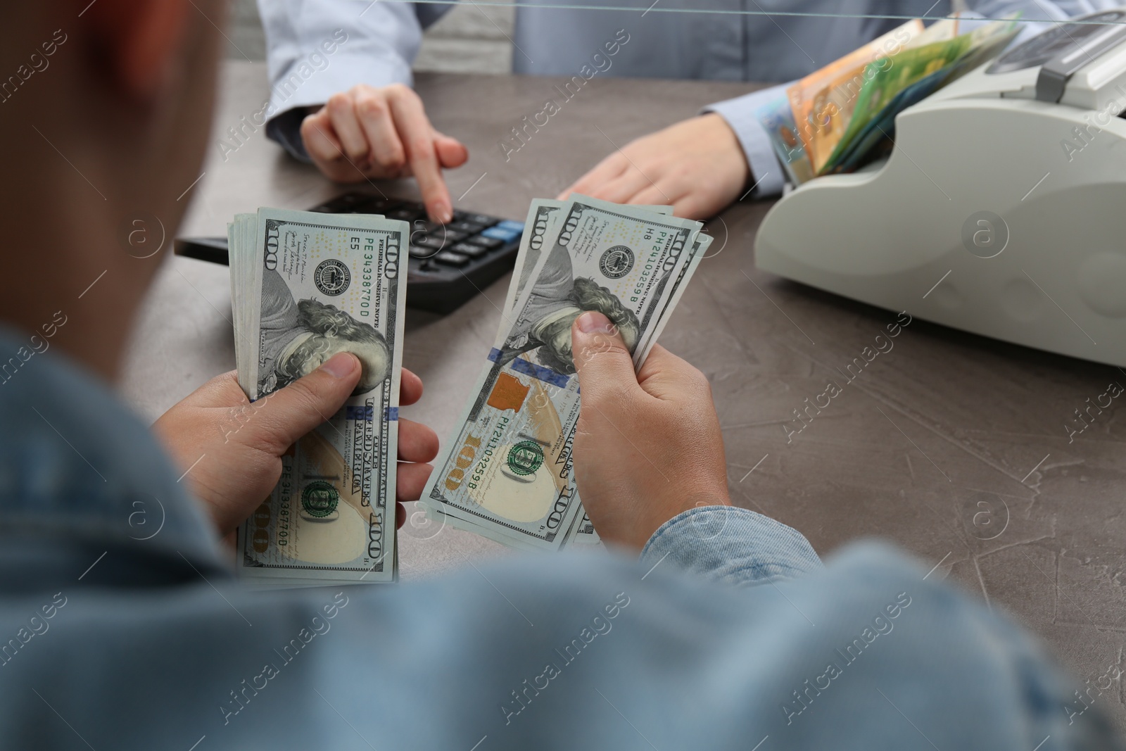 Photo of Client counting money at table in currency exchange, closeup