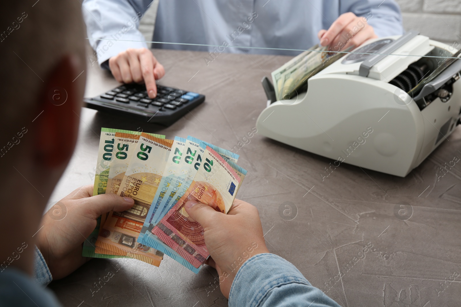 Photo of Client counting money at table in currency exchange, closeup