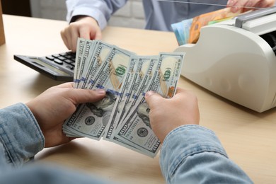 Photo of Client counting money at table in currency exchange, closeup