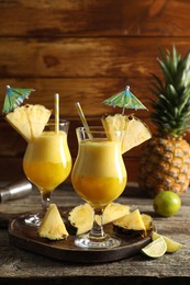 Photo of Tasty pineapple cocktail in glasses served on wooden table