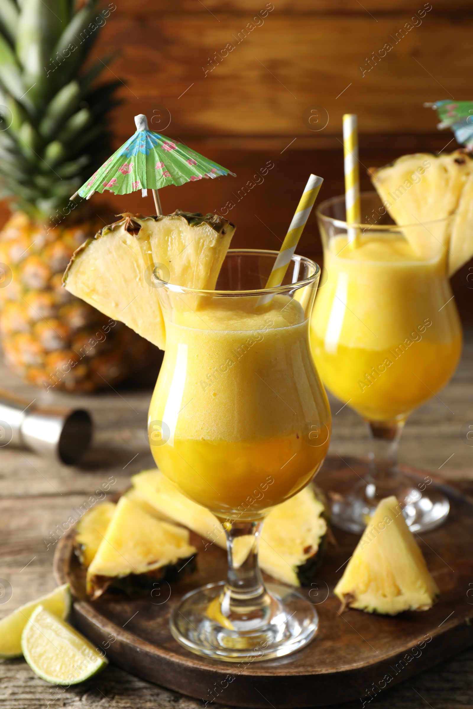 Photo of Tasty pineapple cocktail in glasses served on wooden table