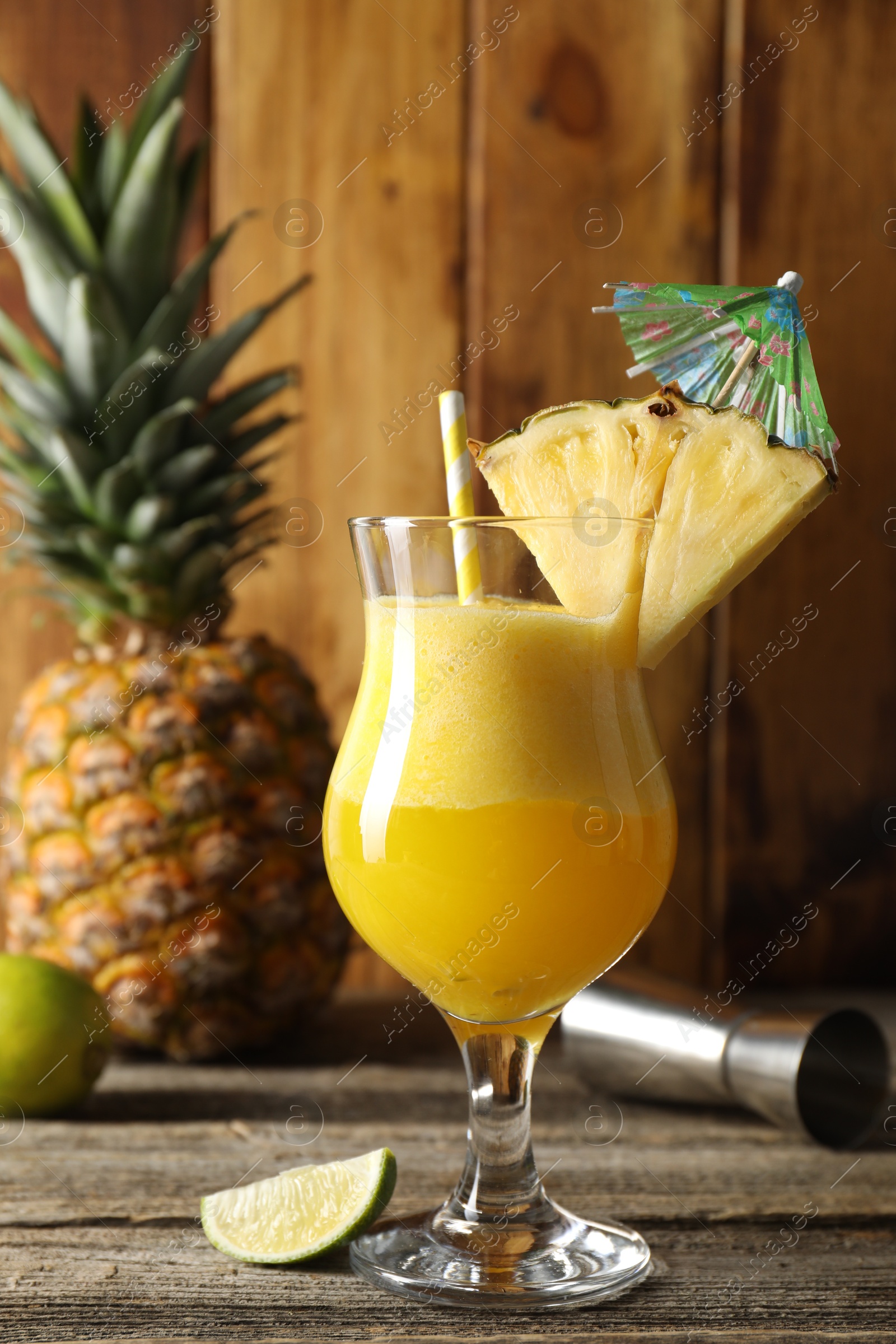 Photo of Tasty pineapple cocktail in glass served on wooden table