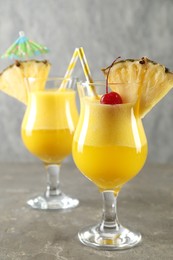 Photo of Tasty pineapple cocktail in glasses served on grey table