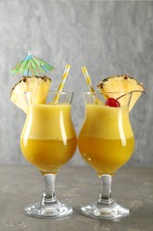 Photo of Tasty pineapple cocktail in glasses served on grey table