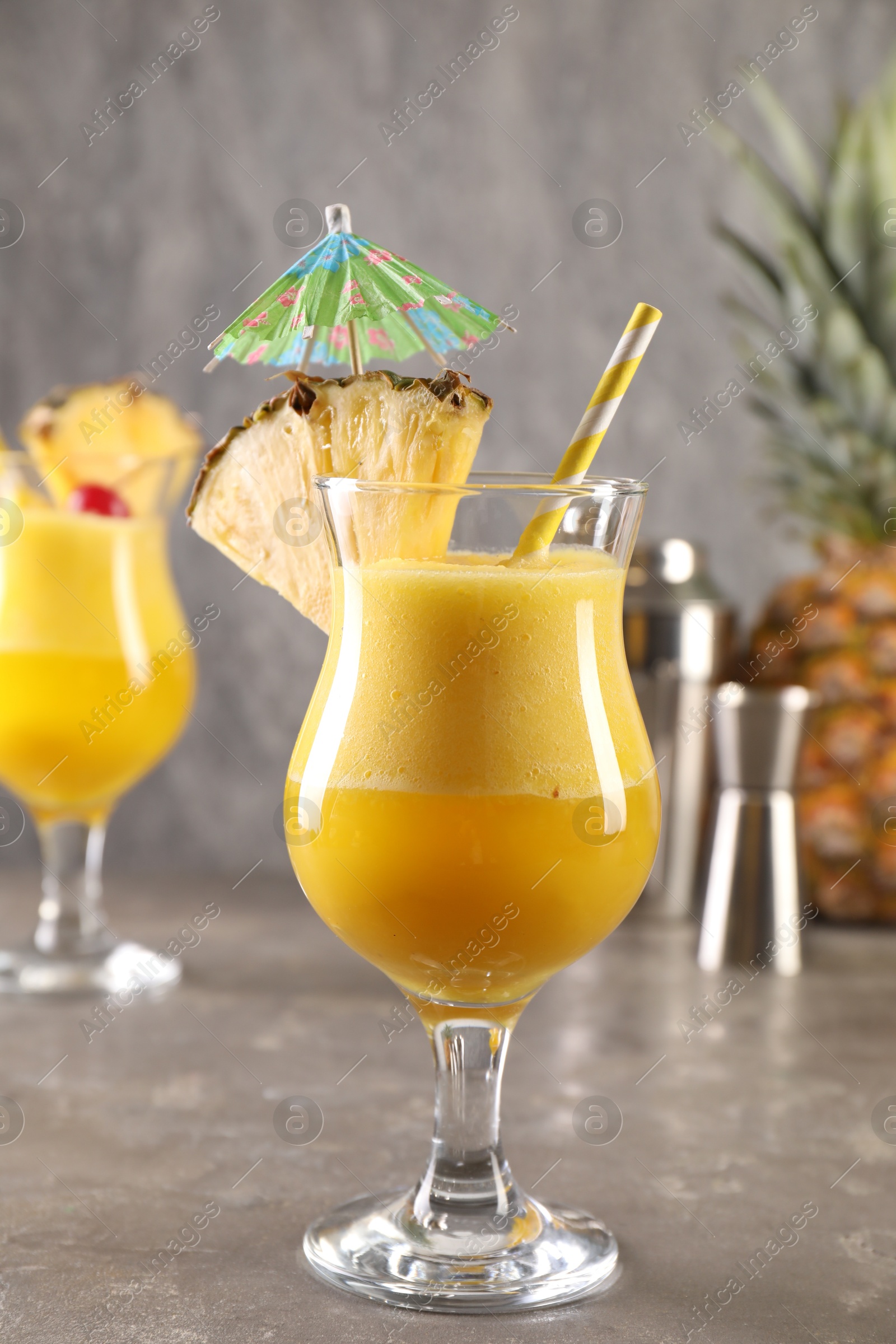 Photo of Tasty pineapple cocktail in glasses served on grey table