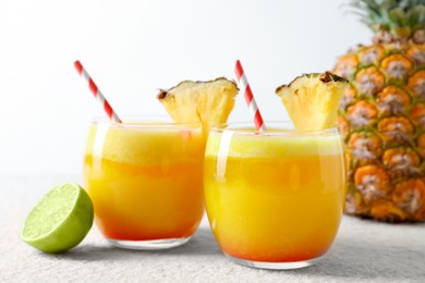 Photo of Tasty pineapple cocktail in glasses served on white table