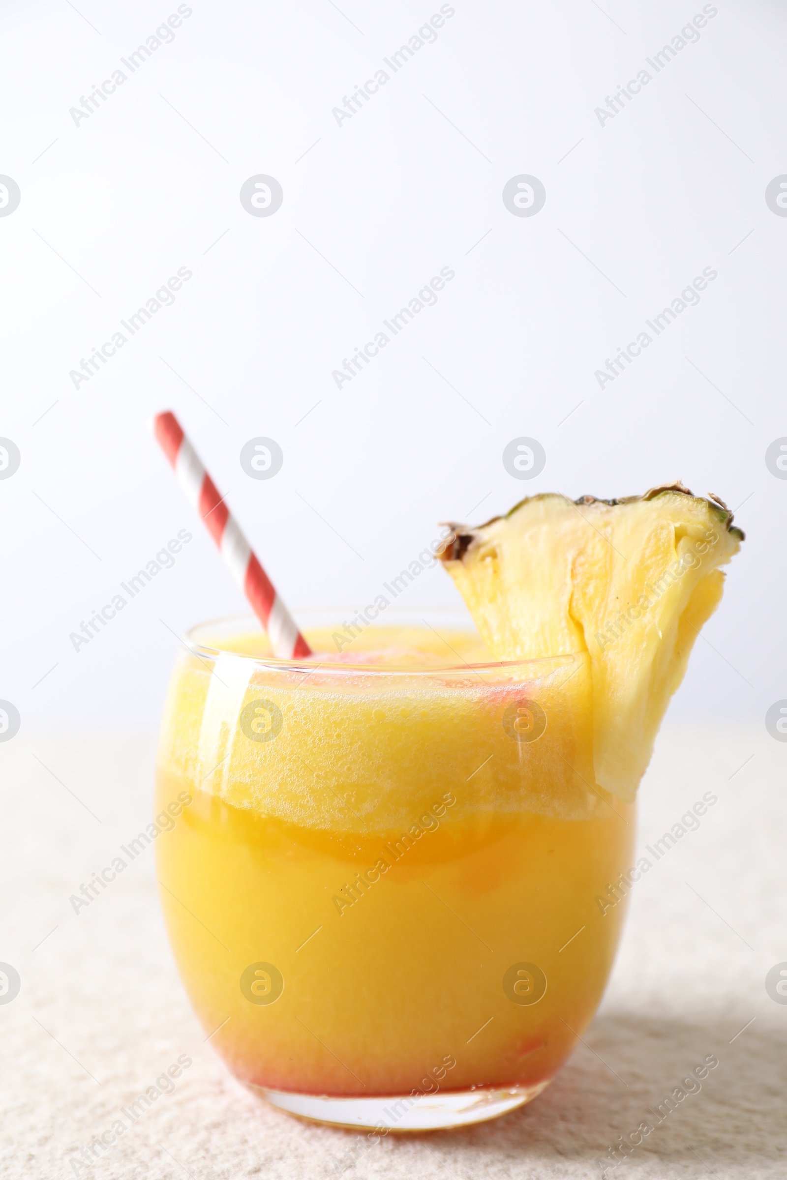 Photo of Tasty pineapple cocktail in glass served on white table