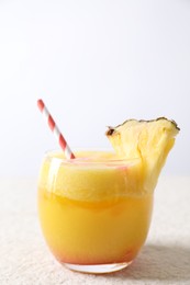 Photo of Tasty pineapple cocktail in glass served on white table