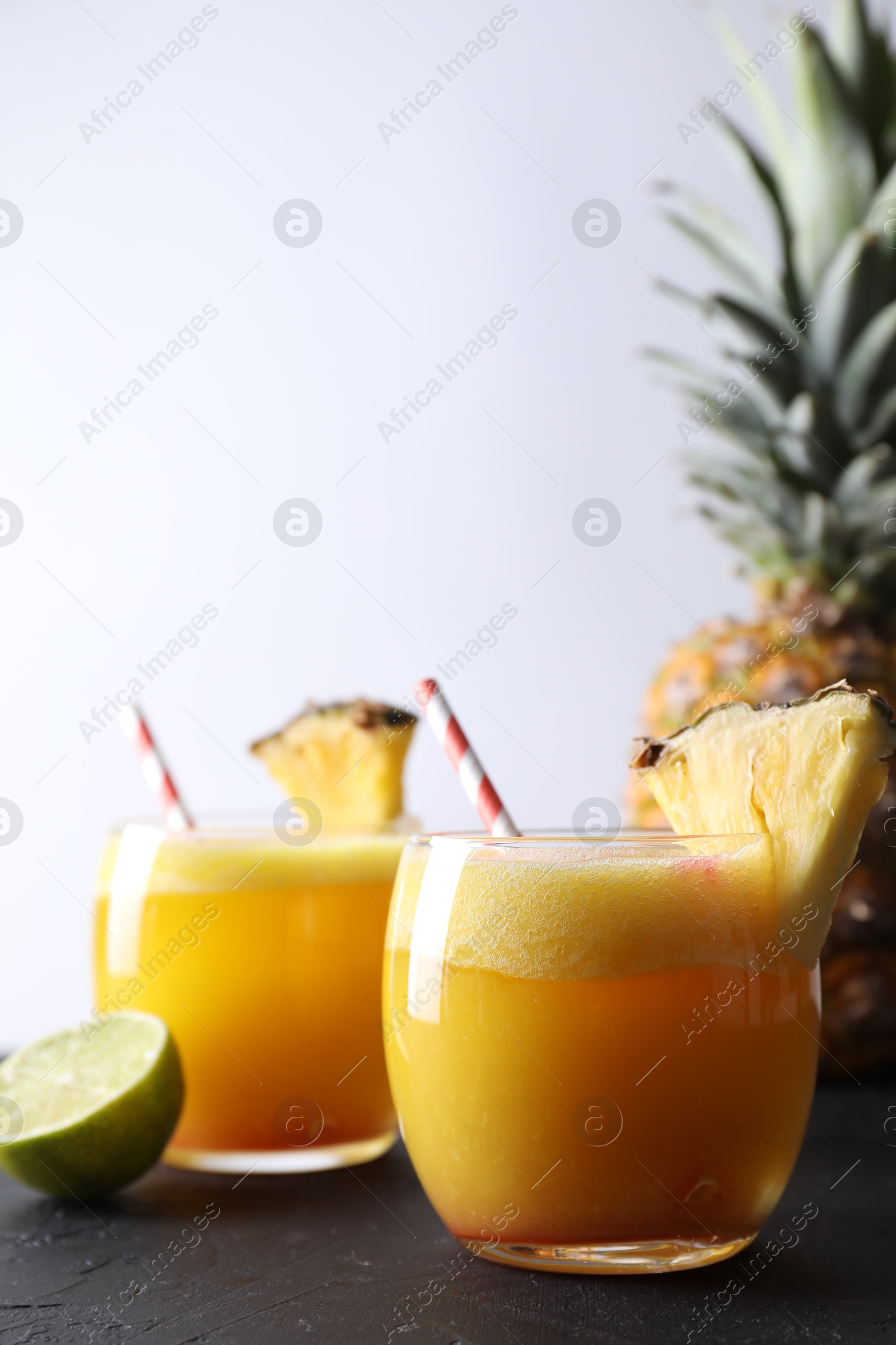 Photo of Tasty pineapple cocktail in glasses served on black table