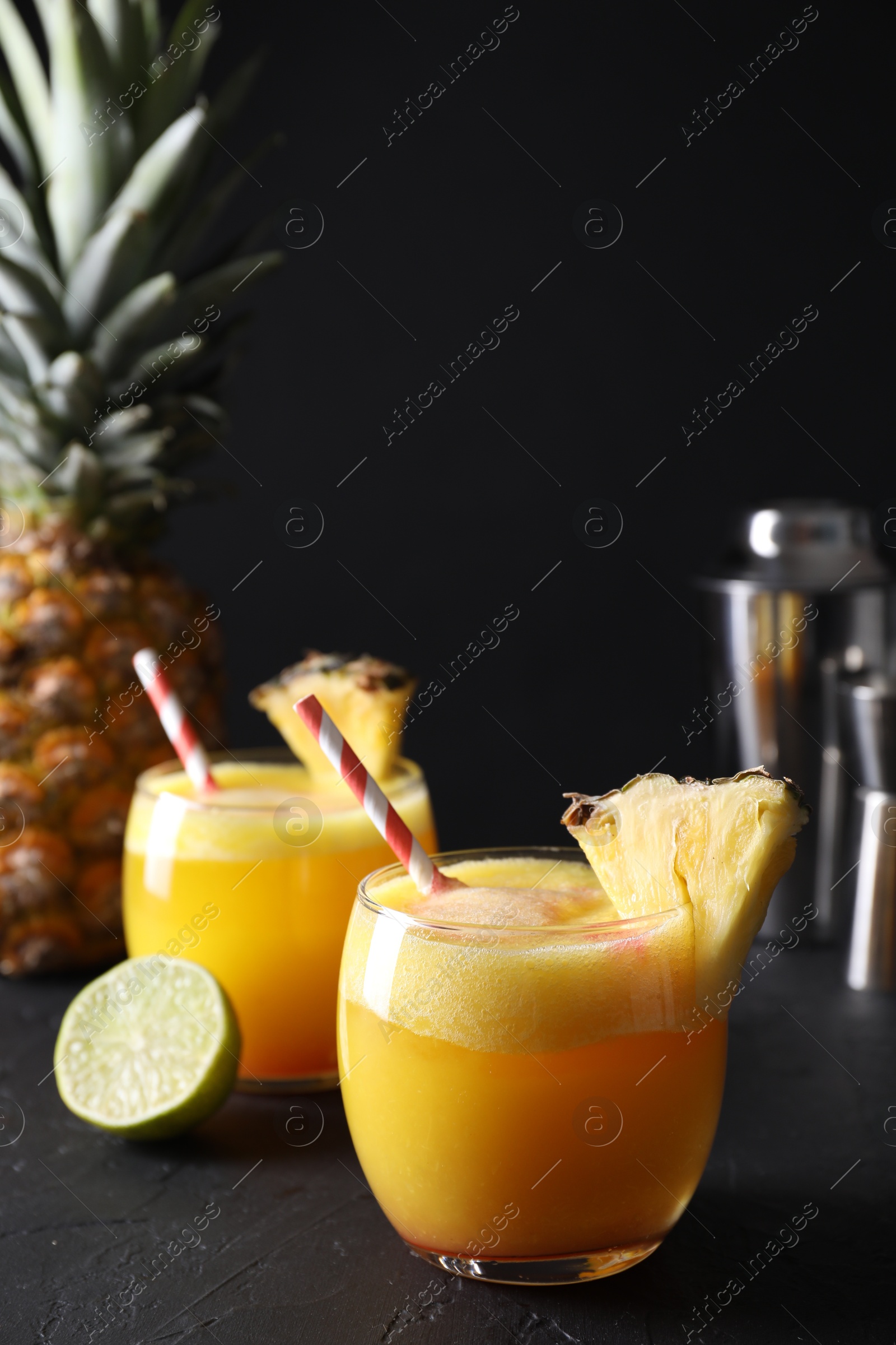 Photo of Tasty pineapple cocktail in glasses served on black table