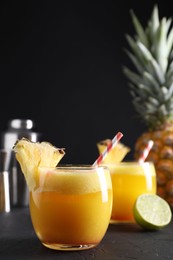 Tasty pineapple cocktail in glasses served on black table