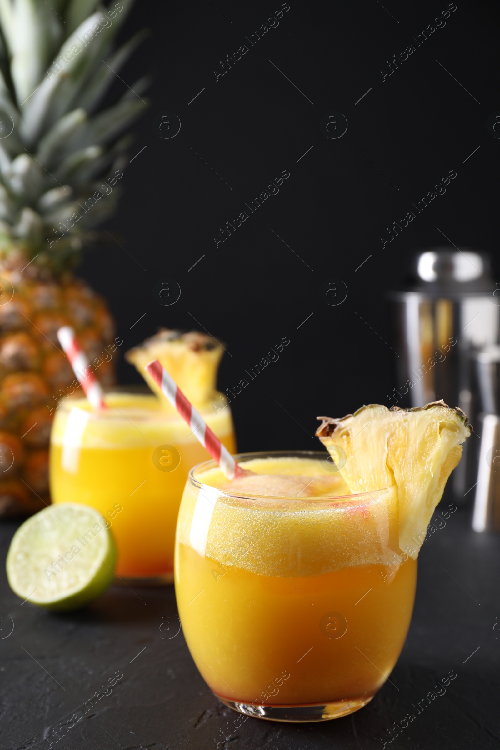 Photo of Tasty pineapple cocktail in glasses served on black table