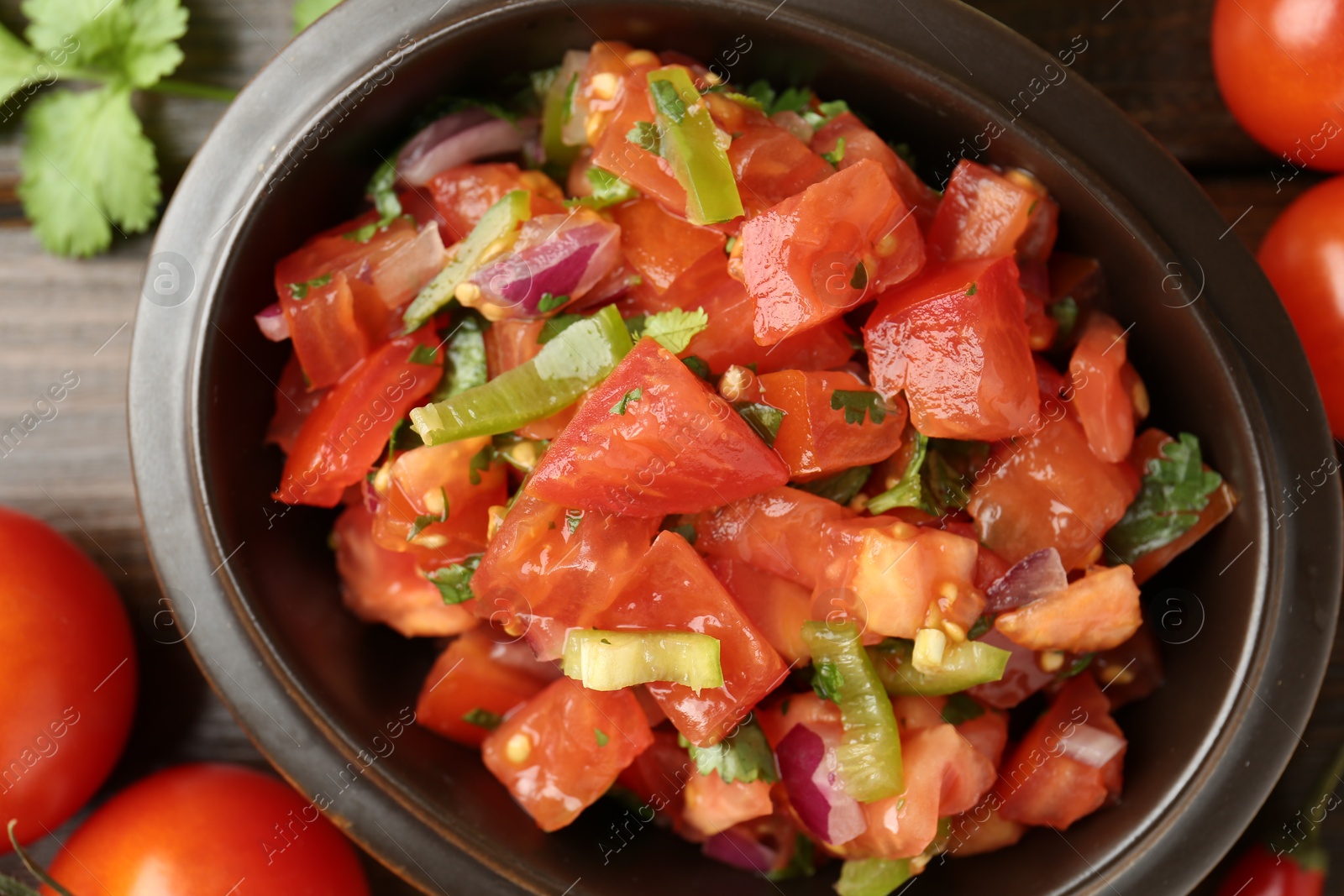 Photo of Delicious spicy salsa with ingredients on wooden table, closeup