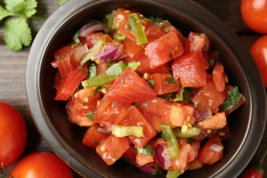 Photo of Delicious spicy salsa with ingredients on wooden table, closeup