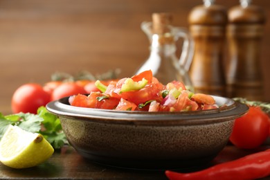 Photo of Delicious spicy salsa with ingredients on wooden table, closeup