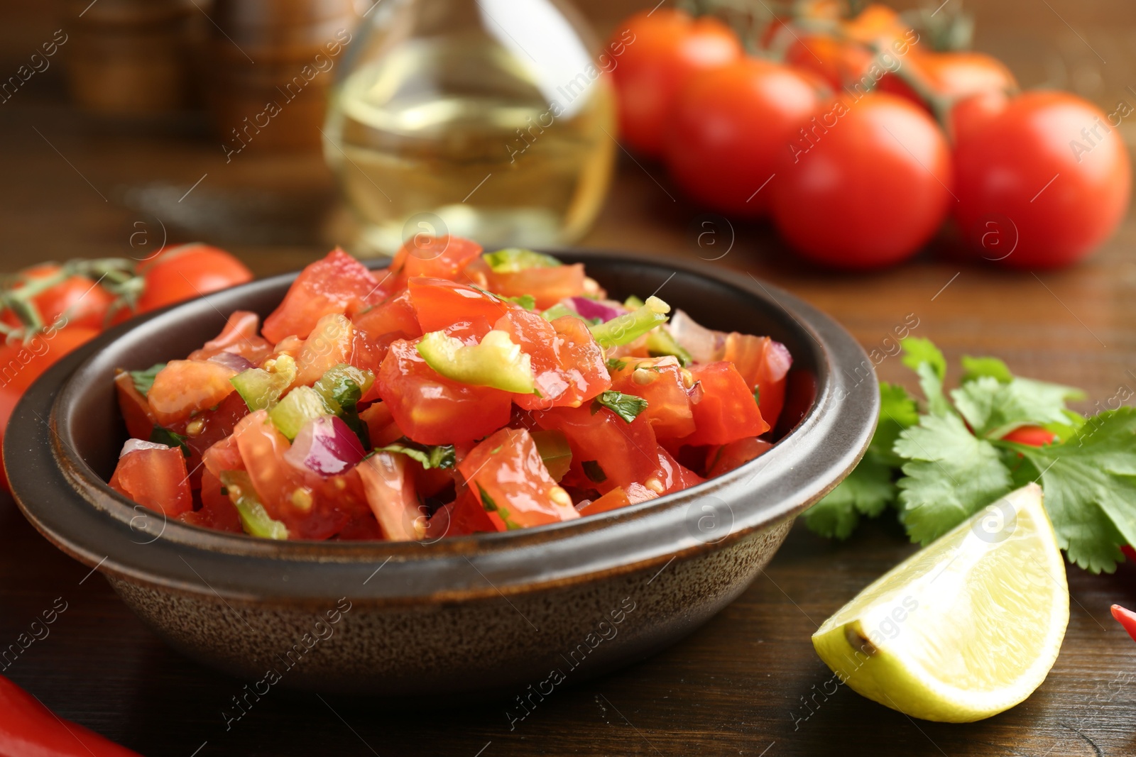 Photo of Delicious spicy salsa with ingredients on wooden table, closeup