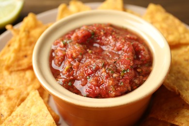 Photo of Delicious homemade salsa with nachos on plate, closeup