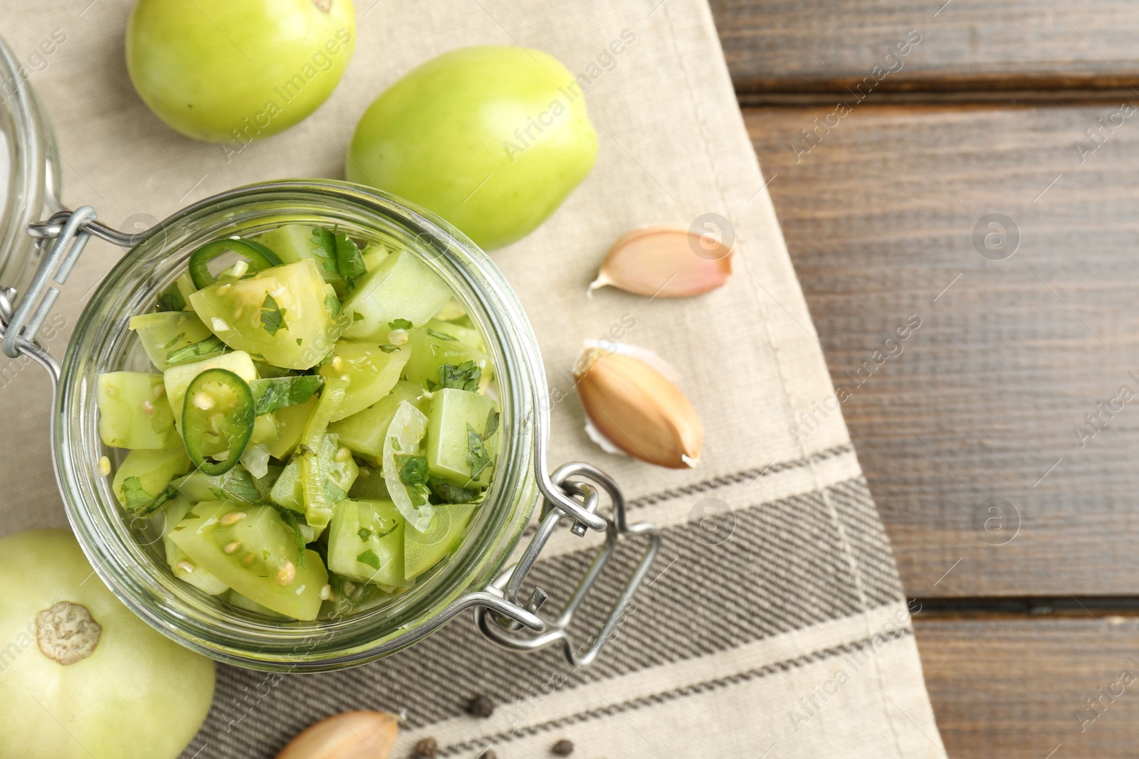 Photo of Delicious green salsa in jar and ingredients on wooden table, flat lay