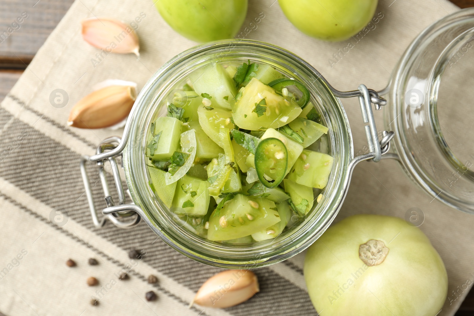 Photo of Delicious green salsa in jar and ingredients on wooden table, flat lay