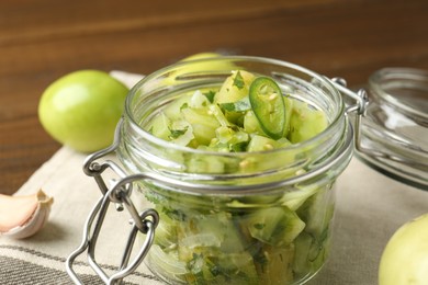 Photo of Delicious green salsa in jar and ingredients on wooden table, closeup