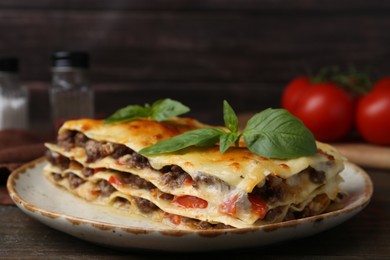 Photo of Delicious cooked lasagna with basil on wooden table, closeup