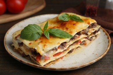 Photo of Delicious cooked lasagna with basil on wooden table, closeup