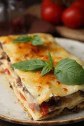 Photo of Delicious cooked lasagna with basil on plate, closeup