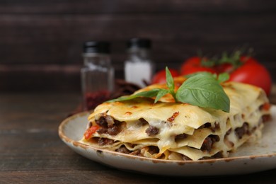 Photo of Delicious cooked lasagna with basil on wooden table, closeup. Space for text