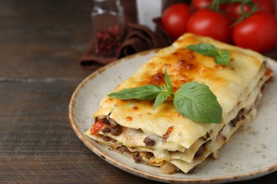 Photo of Delicious cooked lasagna with basil on wooden table, closeup