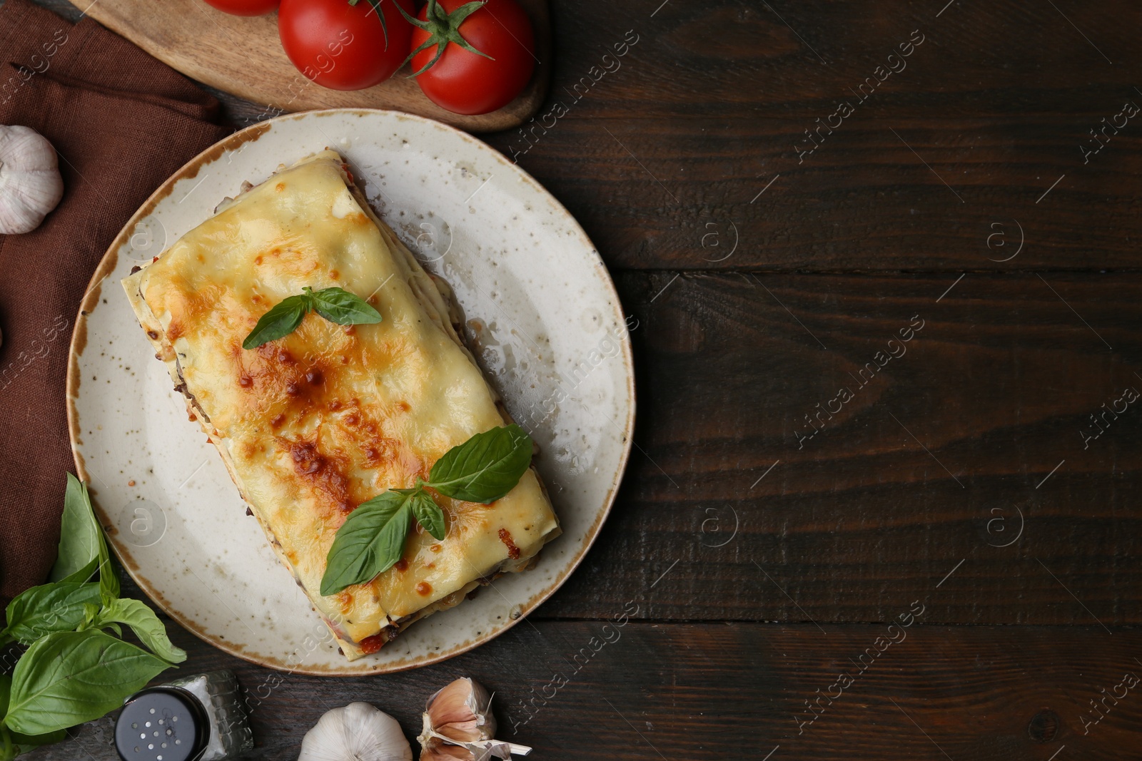 Photo of Delicious cooked lasagna and ingredients on wooden table, flat lay. Space for text