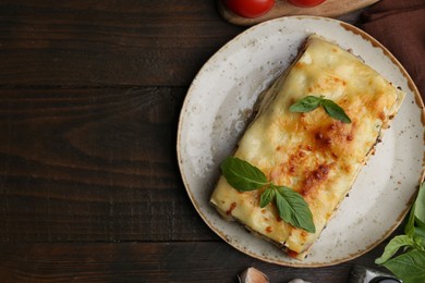 Photo of Delicious cooked lasagna with basil on wooden table, flat lay. Space for text