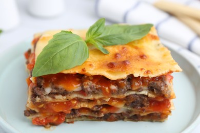 Photo of Delicious cooked lasagna with basil on plate, closeup