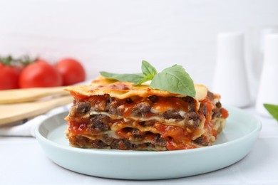 Photo of Delicious cooked lasagna with basil on white table, closeup