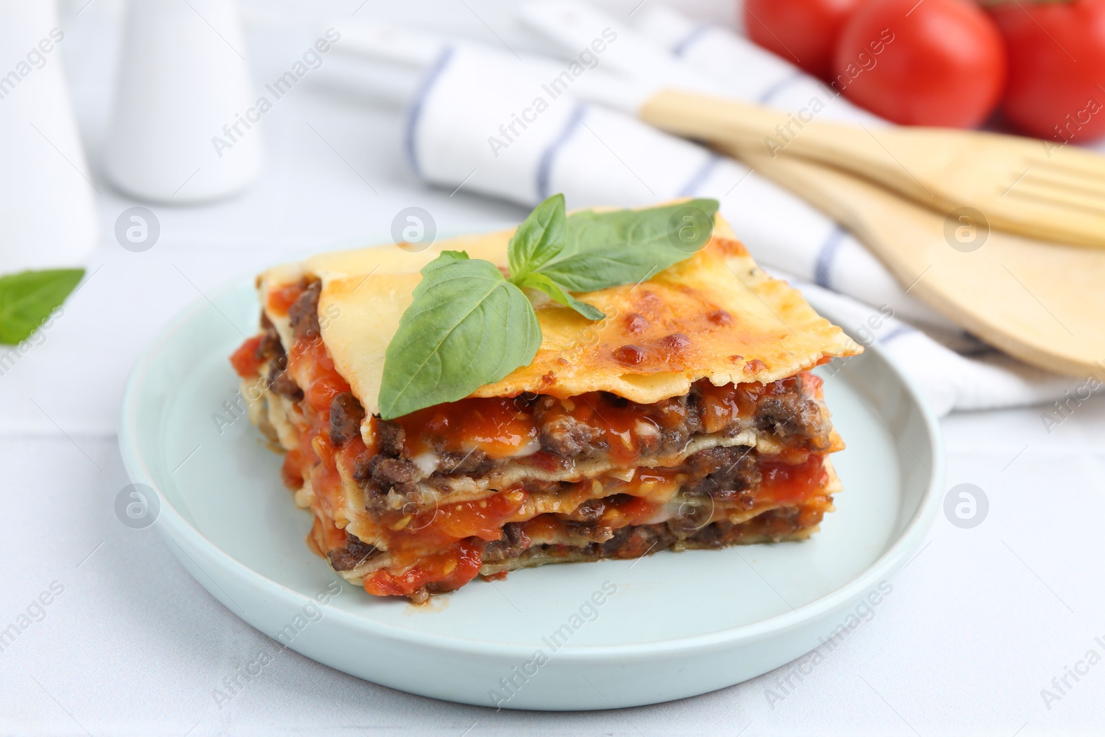 Photo of Delicious cooked lasagna with basil on white table, closeup