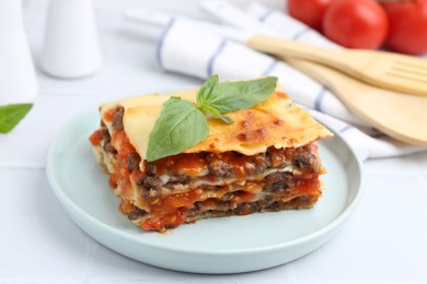 Photo of Delicious cooked lasagna with basil on white table, closeup