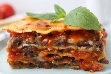 Photo of Delicious cooked lasagna with basil on plate, closeup