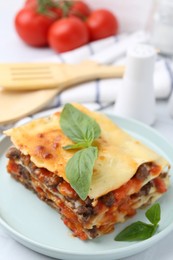 Photo of Delicious cooked lasagna with basil on light table, closeup